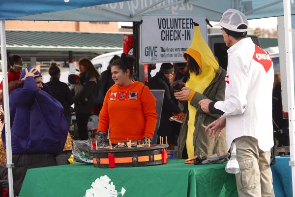 A group of teenagers volunteers to run a booth at a Farmer's Market.