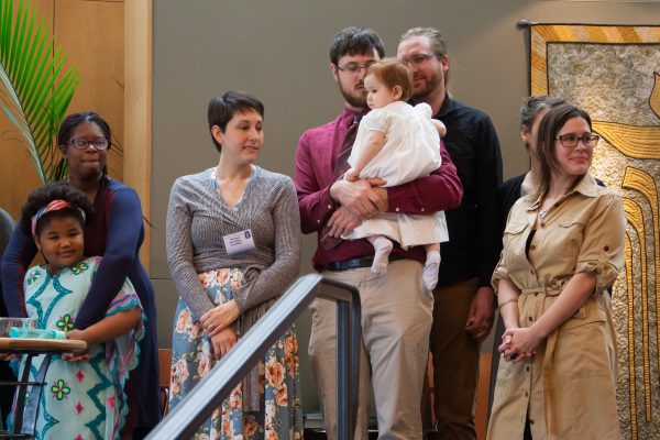 A father holds his baby while he and his wife and family listen to the words of the Child Dedication Ceremony.