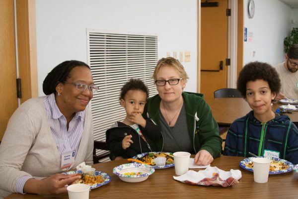 A couple and their two children eat dinner together during a social gathering.
