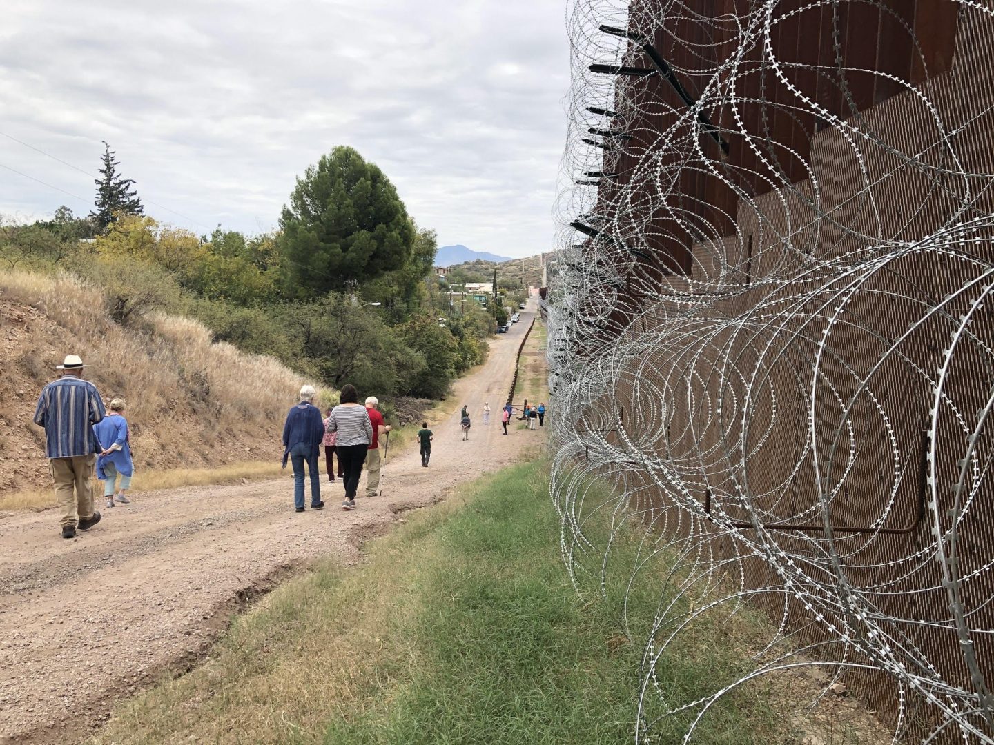 A group of people walk along the US-Mexico border wall during an experiential learning trip to Arizona.