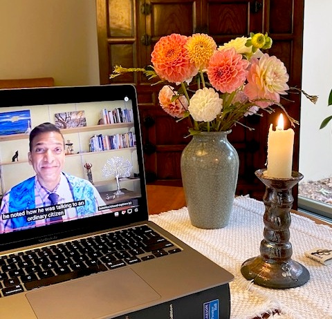 An open laptop plays a video of a minister preaching.